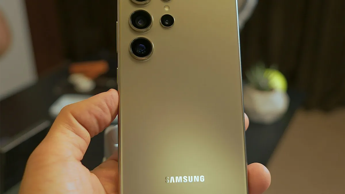 The back of a gold Samsung Galaxy phone held in one hand
