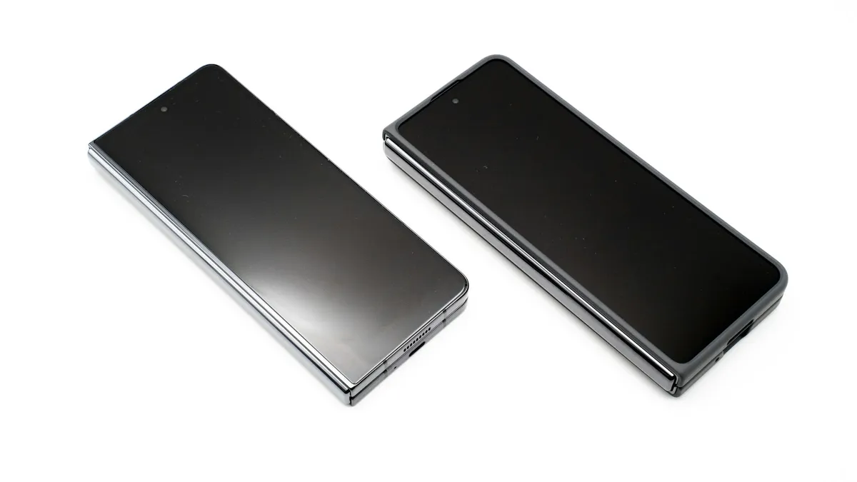Two black cell phones side by side on a white surface