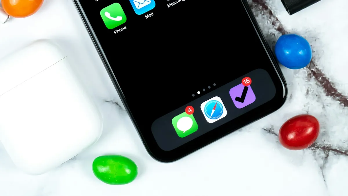 An iPhone and an Apple Watch lying side by side on a marble desk