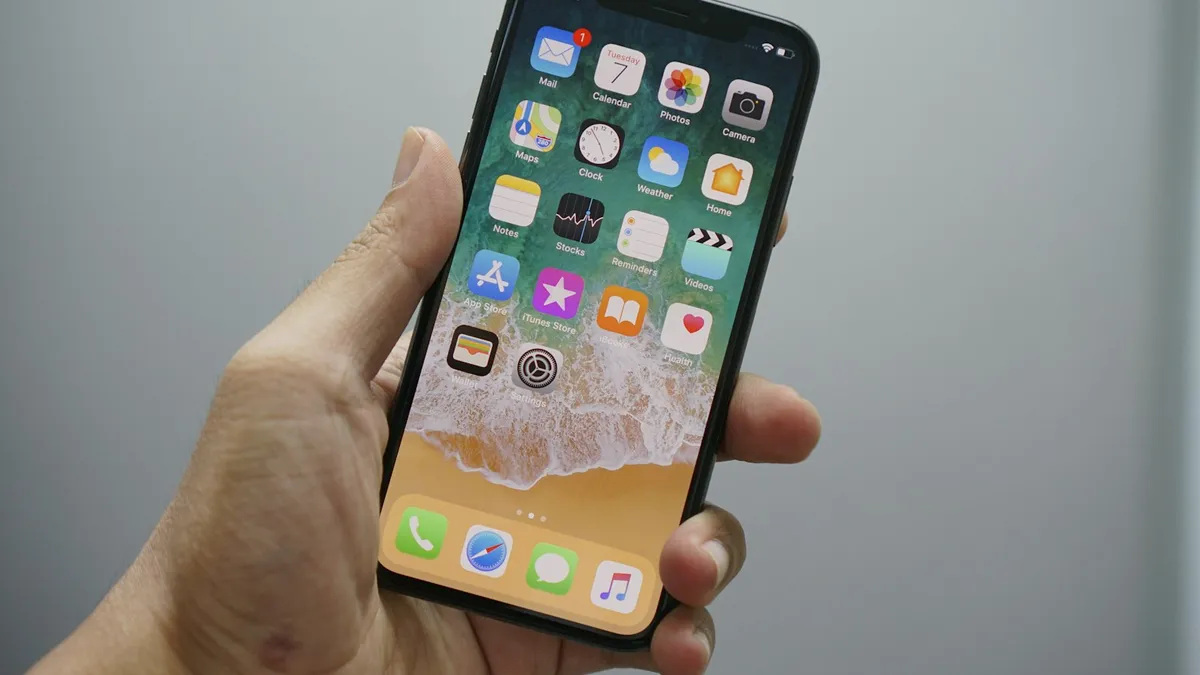 A hand holding a smartphone showing a home screen with app icons