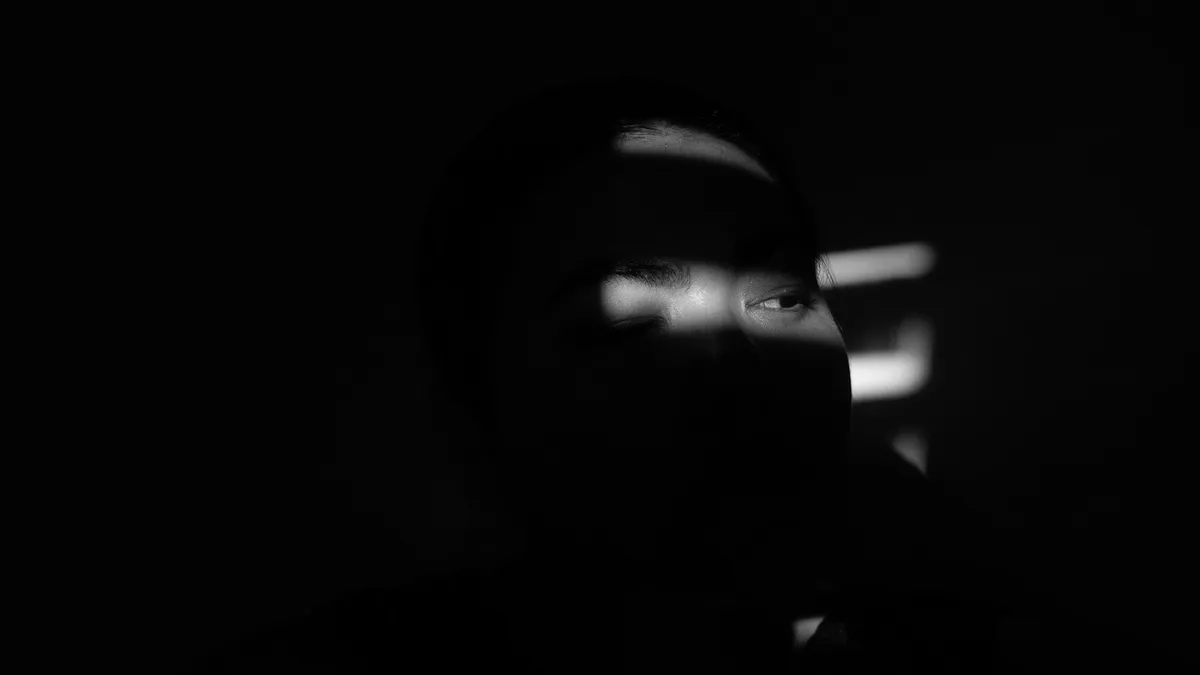 A person in a dark room lit only by a phone screen