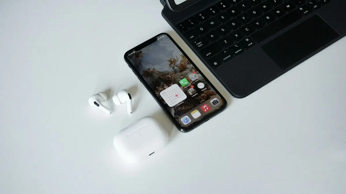 An iphone, ear buds, and laptop on a table