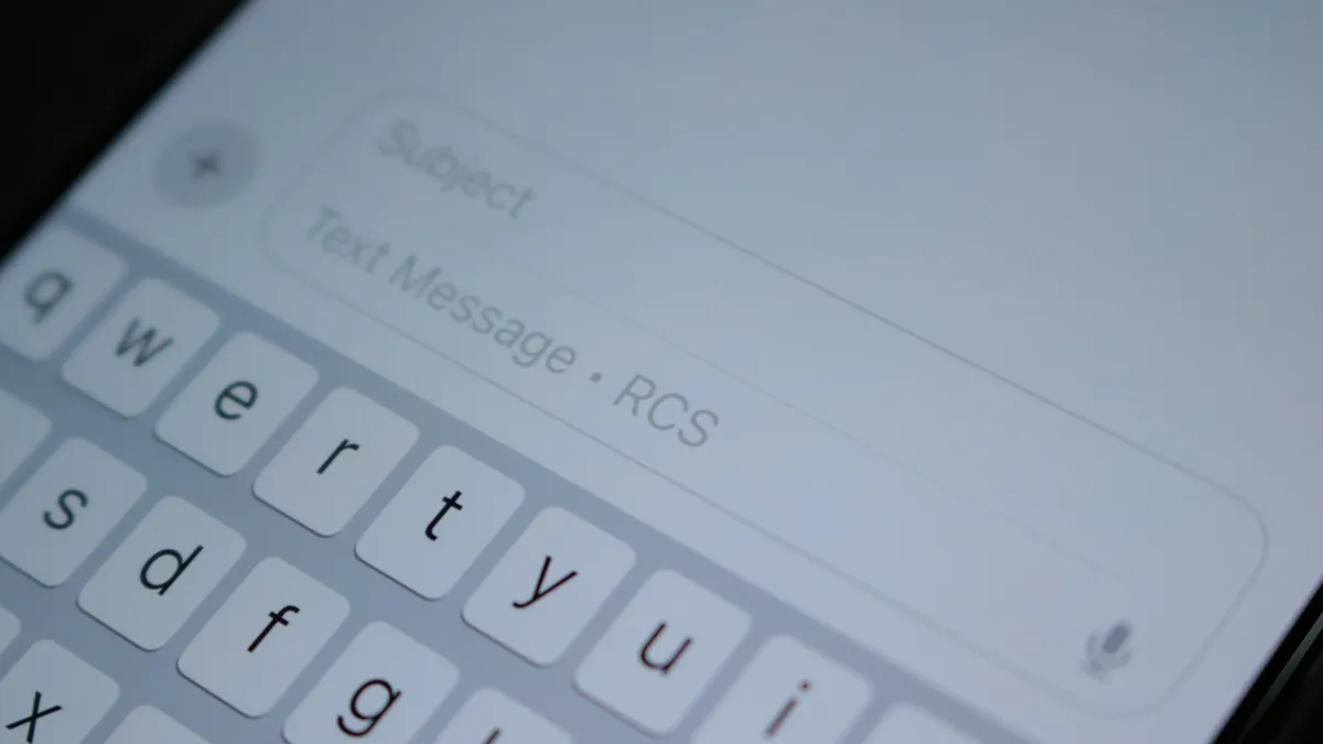 A close up of the on-screen keyboard on an iPhone with a new message open