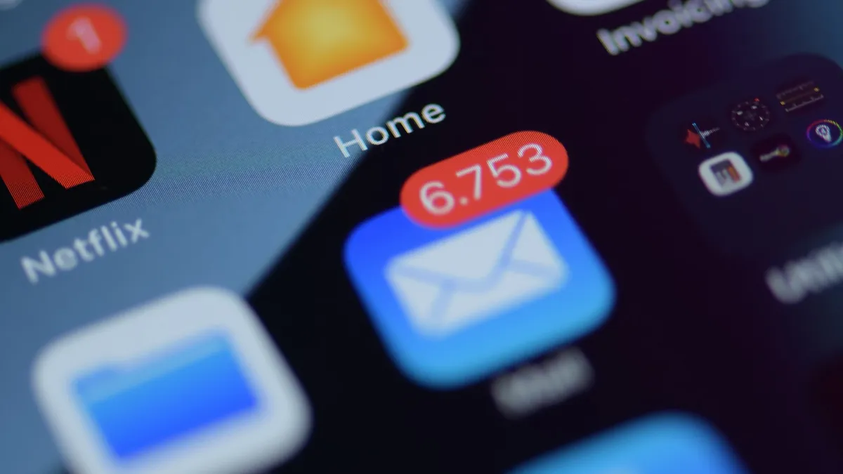 A close up of an iPhone Home Screen with app icons and a red notification badge on Mail