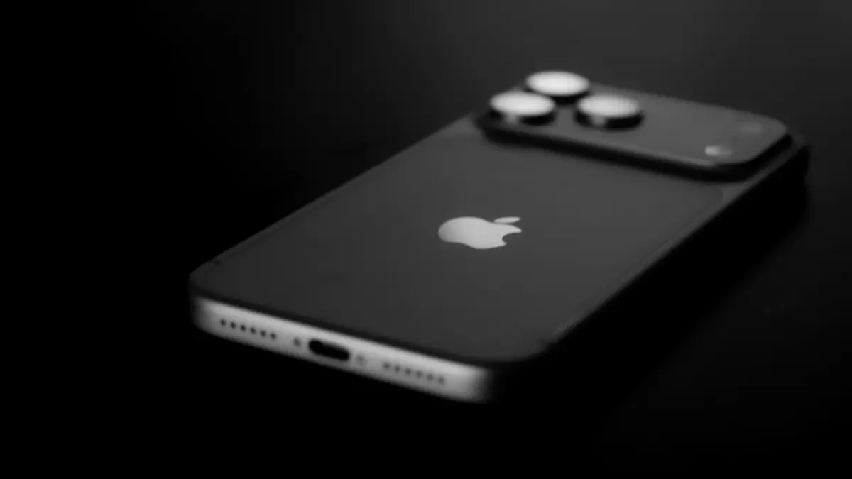 A dark smartphone lies on a black surface