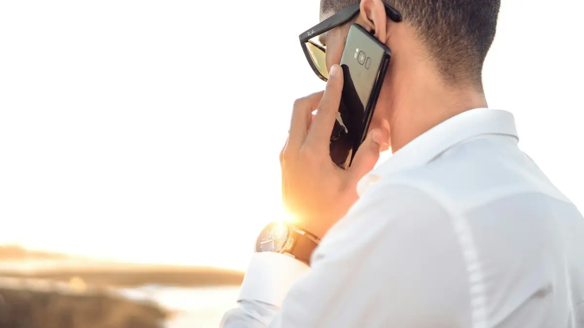 Man holding smartphone standing in front of calm body of water
