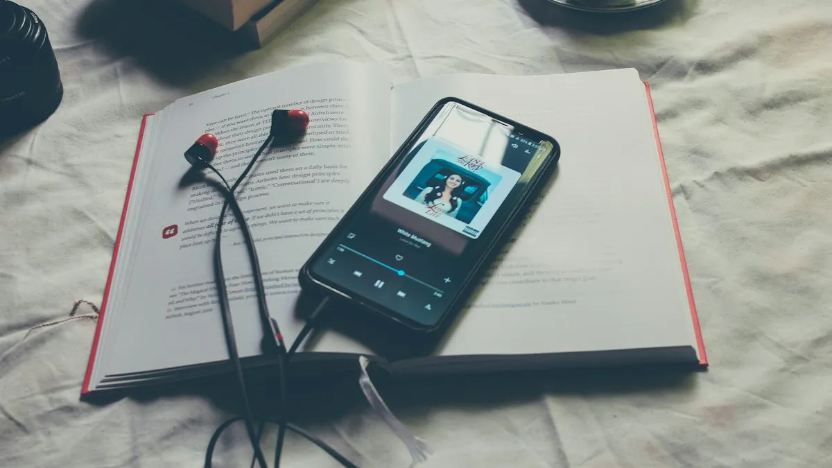 A black Android phone with earphones plugged in, lying on a book