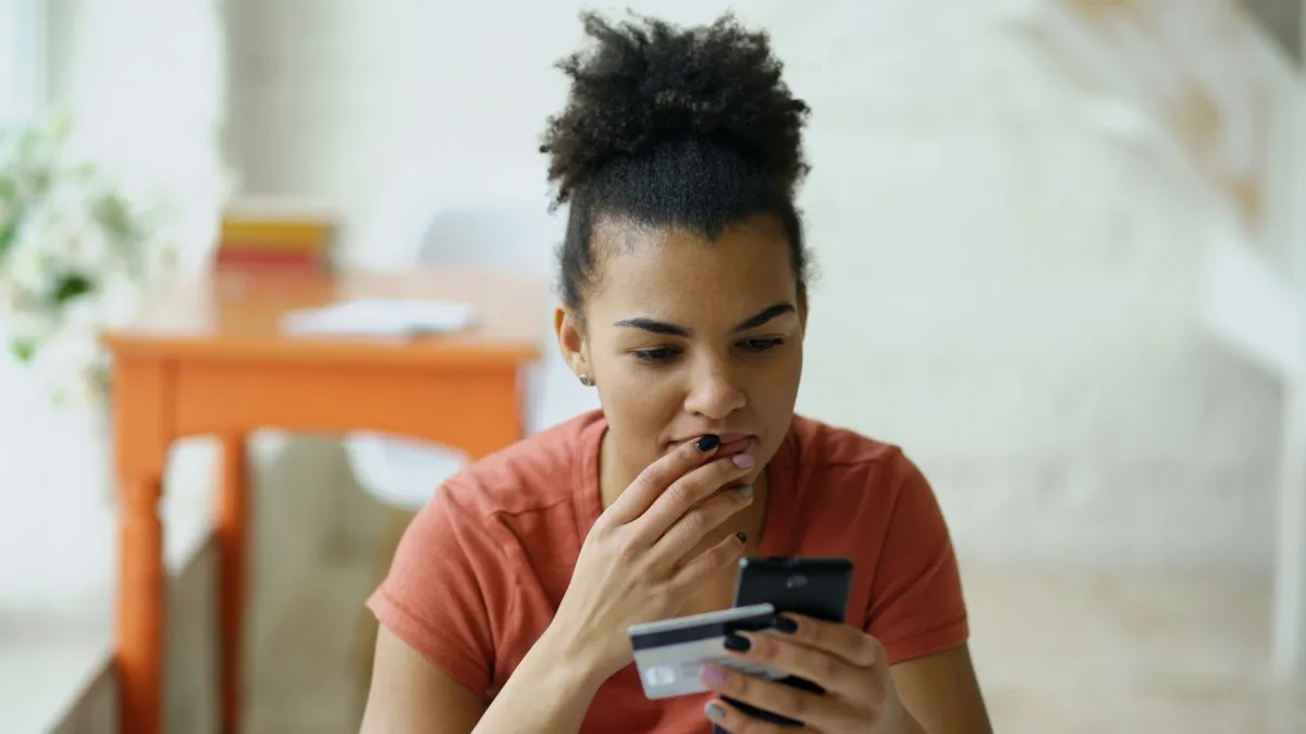 A woman looking at a phone with a credit card in her hand