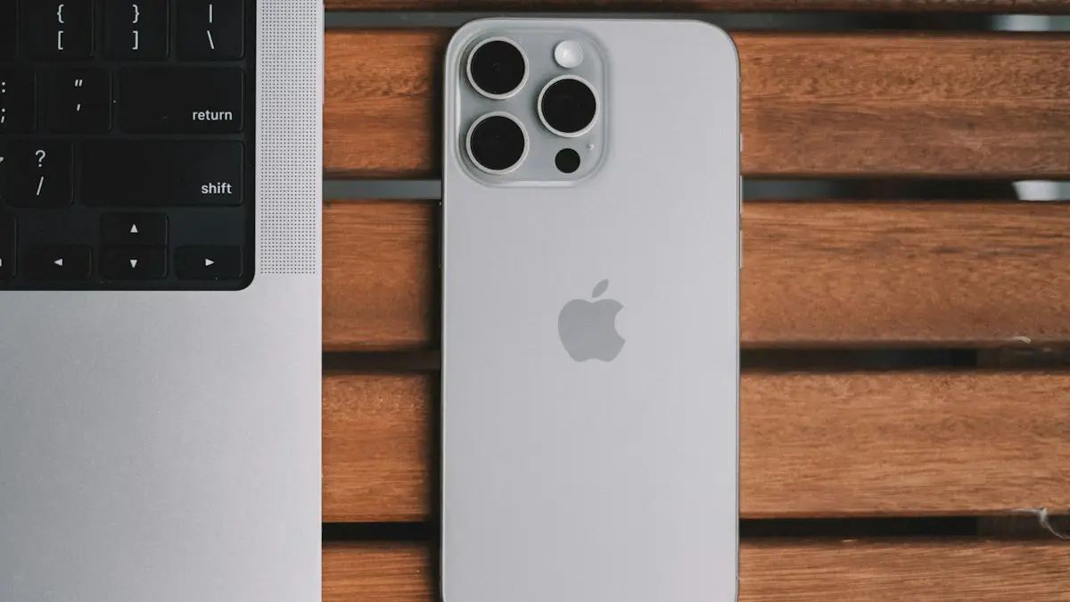 An iPhone and a laptop on a wooden table