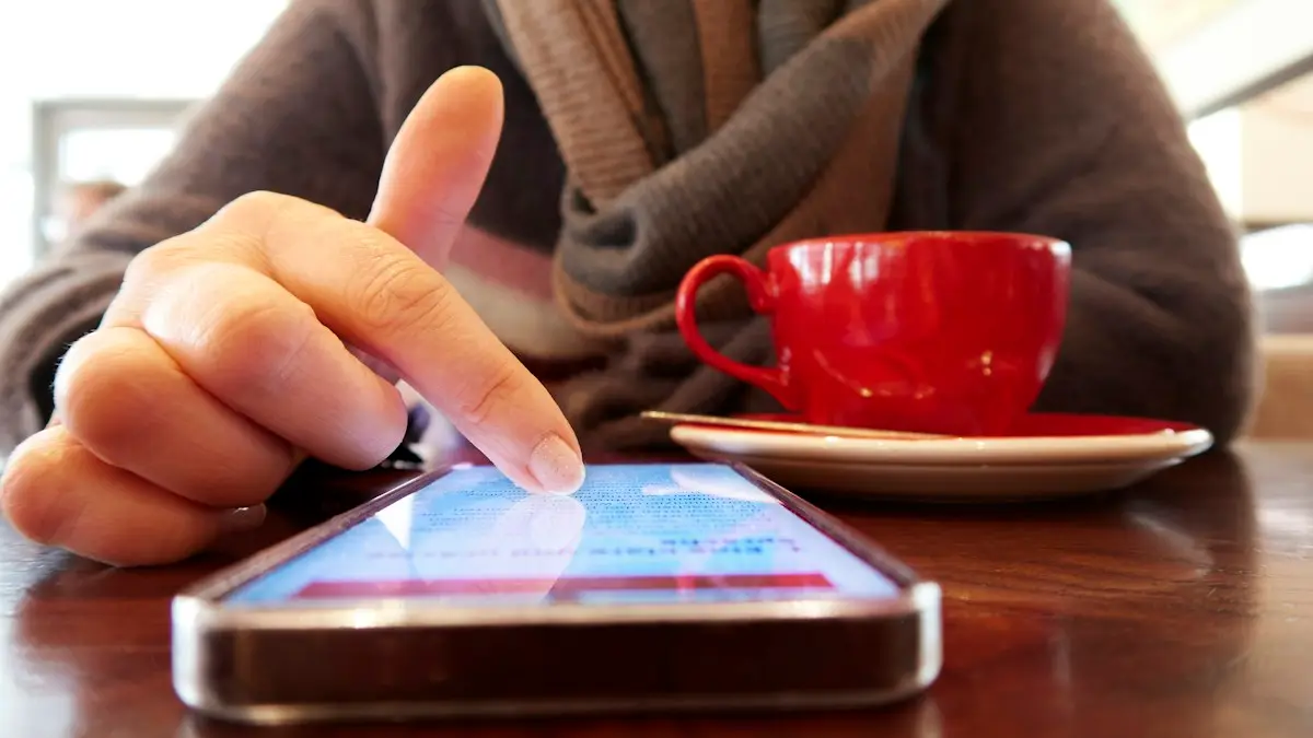 Person using a smartphone with a cup of coffee