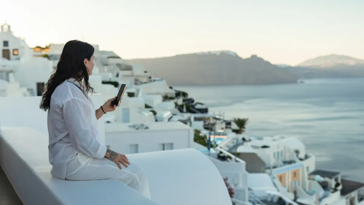 Woman with phone overlooking a white village and sea